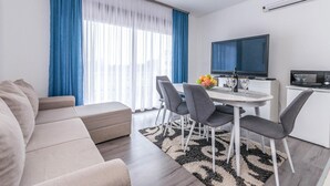 Una sala de estar moderna con sofá, mesa de comedor, sillas y televisor.