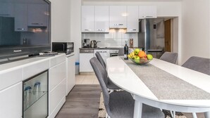 Una cocina moderna con armarios blancos, horno empotrado y refrigerador de acero inoxidable.