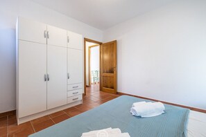 A bedroom with a bed, a wardrobe, and a wooden door. - Coastal Apartments - Comfort (Cabras)