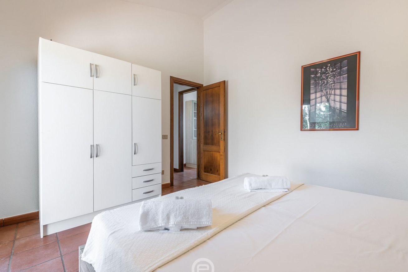 A bedroom with a bed, a wardrobe, and a framed picture on the wall.
