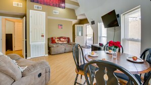 A spacious living room with a dining area, a staircase, and a TV mounted on the wall. - Quiet, Quirky Country Escape Near Pearl River! (Angie)