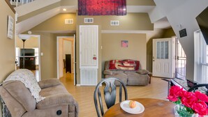 A spacious living area with a high ceiling, a staircase, a dining table with a plate of fruit, and a couch. - Quiet, Quirky Country Escape Near Pearl River! (Angie)