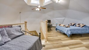 A spacious loft bedroom with a high ceiling, a wooden staircase, a ceiling fan, and a large window providing natural light. - Quiet, Quirky Country Escape Near Pearl River! (Angie)