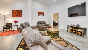 A modern living room with a sectional sofa, a recliner, a coffee table, and a TV mounted on the wall. - Unique Country Getaway in Angie w/ Covered Patio! (Angie)