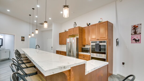 A modern kitchen with a large island, stainless steel appliances, wooden cabinets, and pendant lighting. - Unique Country Getaway in Angie w/ Covered Patio! (Angie)