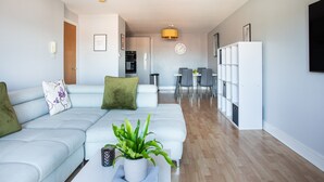 A modern living room with a light blue sofa, a coffee table with a plant, and a dining area with chairs and a table. - 5* Ultra Luxury, Great Views, Underground Parking (Belfast)