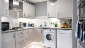 A modern kitchen with white cabinets, a built-in dishwasher, a microwave, and a gas stove. - 5* Ultra Luxury, Great Views, Underground Parking (Belfast)