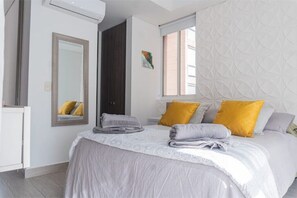 Relax in a serene bedroom with a large bed, mirror, and minimalist design.