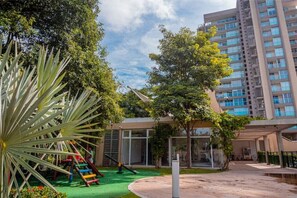 Guests can enjoy a playground with a slide and climbing structures amidst lush greenery and trees.