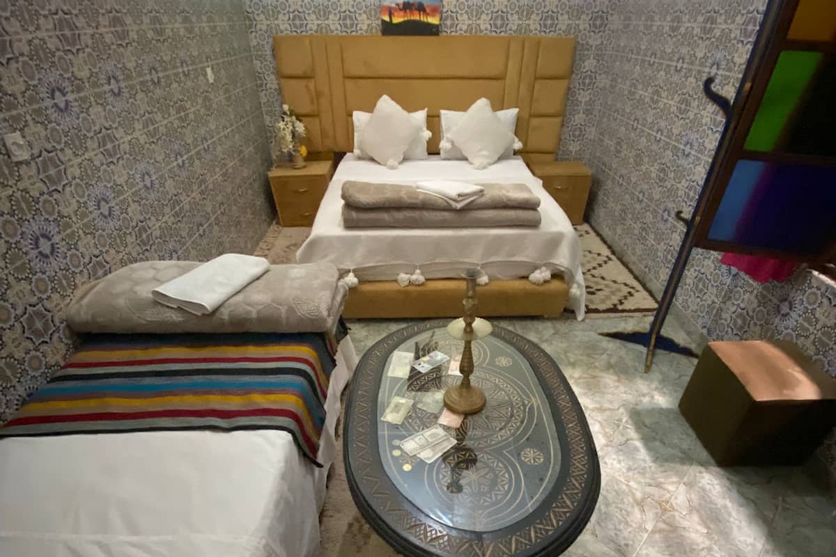 A room with a bed, a small table, and a patterned rug.