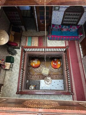 A traditional room with a wooden bed, a patterned rug, and a small table with a lamp. - Dar Merzouga Meknes (Meknes)