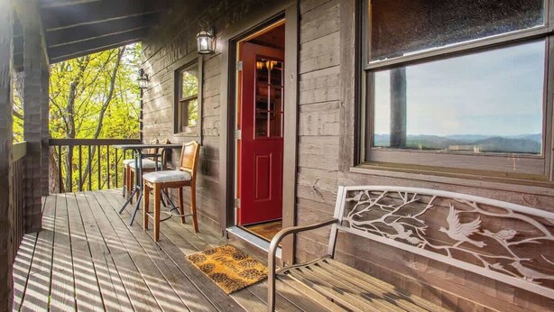 A wooden cabin with a porch, a red door, and a bench. - The Nest - Pickle Ball, Firepit, Hot Tub, Mt Views (Sevierville)