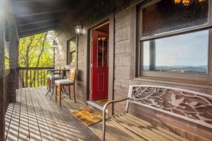 Une cabane en bois avec une véranda, une porte rouge et un banc.