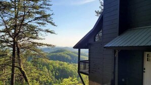 A cabin with a balcony overlooking a forested valley. - The Nest - Pickle Ball, Firepit, Hot Tub, Mt Views (Sevierville)