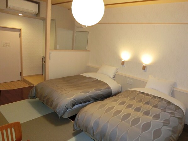 Une chambre d’hôtel avec deux lits, une chaise, un bureau et un miroir.