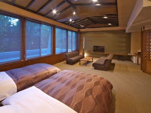 A modern bedroom with a large bed, a sofa, and a TV.