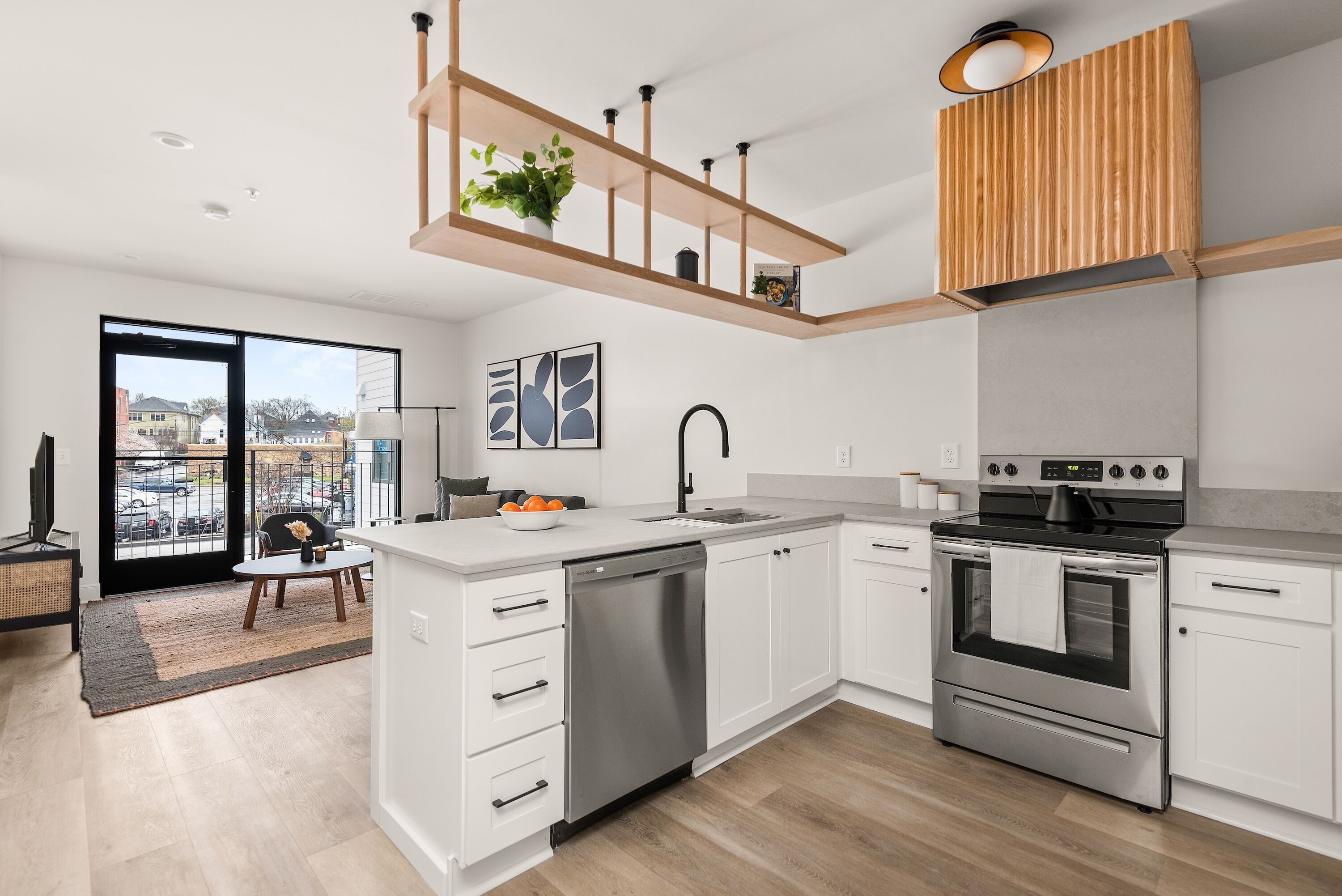Een moderne keuken met witte kasten, roestvrijstalen apparatuur en een houten plafondplank.