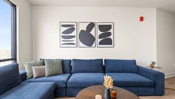 A modern living room with a blue sectional sofa, a round coffee table, and abstract wall art.
