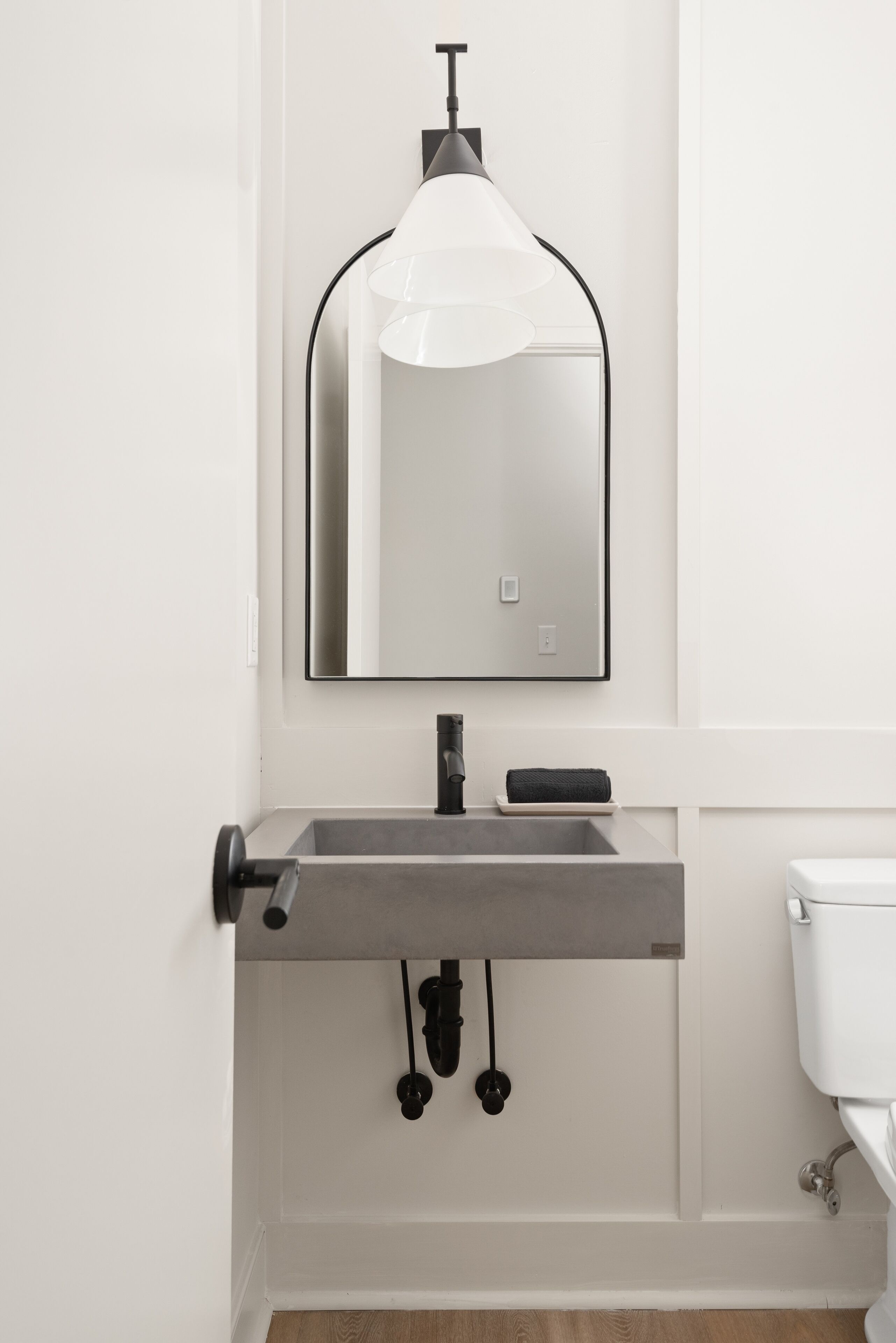 A modern bathroom with a rectangular sink, a large mirror, and a toilet.