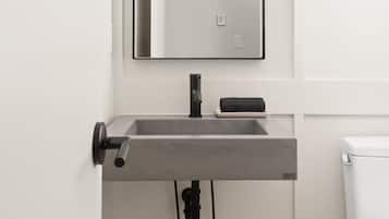 A modern bathroom with a rectangular sink, a large mirror, and a toilet.