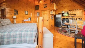 A cozy log cabin with a bed, a small table, and a kitchen area. - Nuthouse - Pickle Ball, Firepit, mountain views (Sevierville)