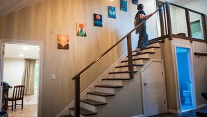 Una escalera con barandilla, una puerta al final y una pared con varias obras de arte enmarcadas.