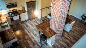 Una cocina moderna con piso de madera, un pilar de ladrillo y un comedor con una mesa y sillas.