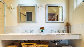 A bathroom with two sinks, wooden ceiling, and wicker baskets under the counter.