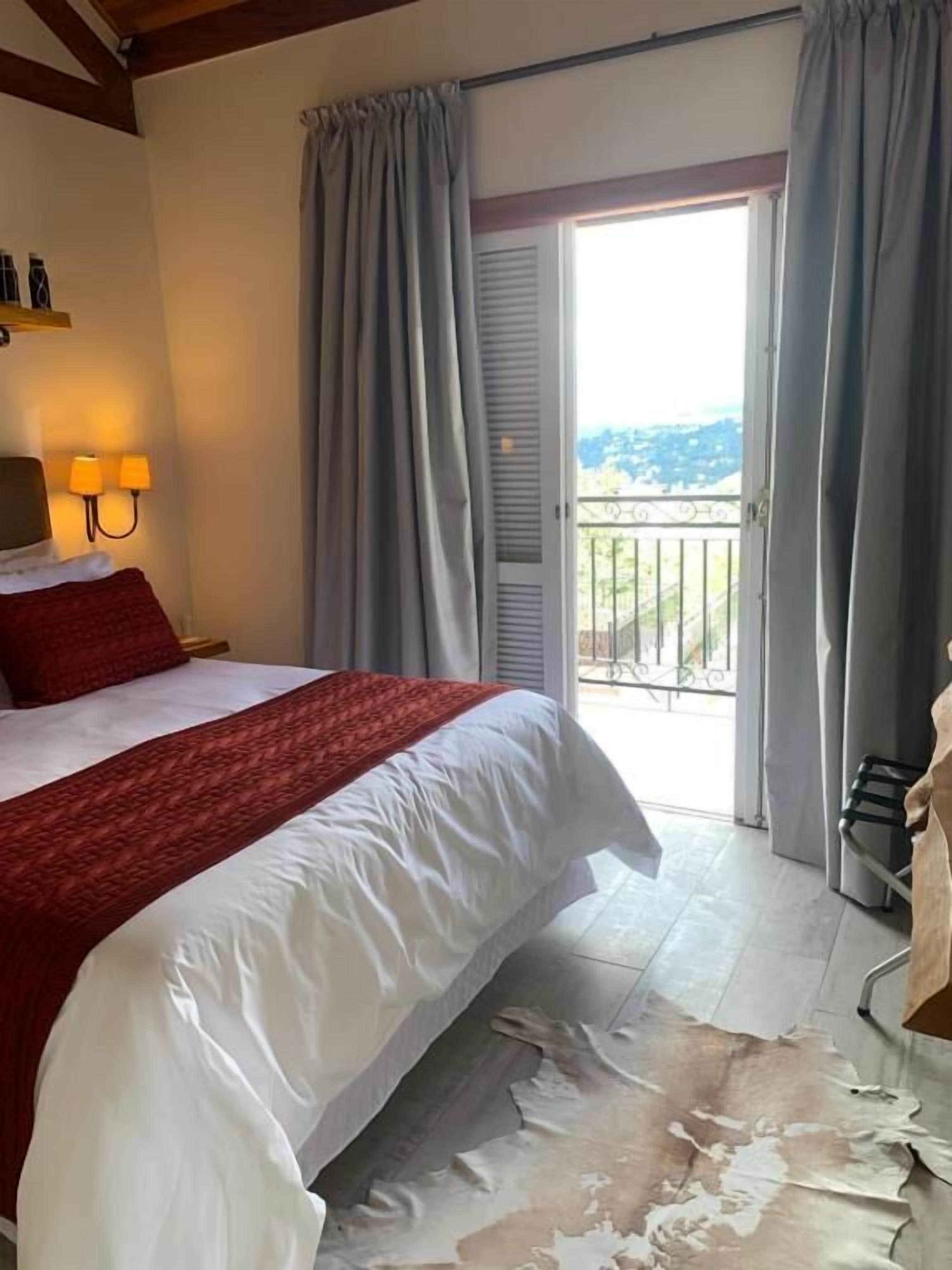 Une chambre avec un grand lit, un balcon et une vue sur l’extérieur.
