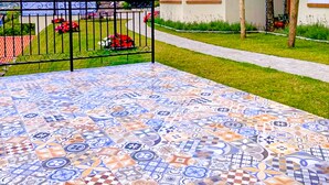 A house with a tiled patio and a fenced garden area.