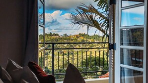 A balcony with a view of a green landscape and houses.