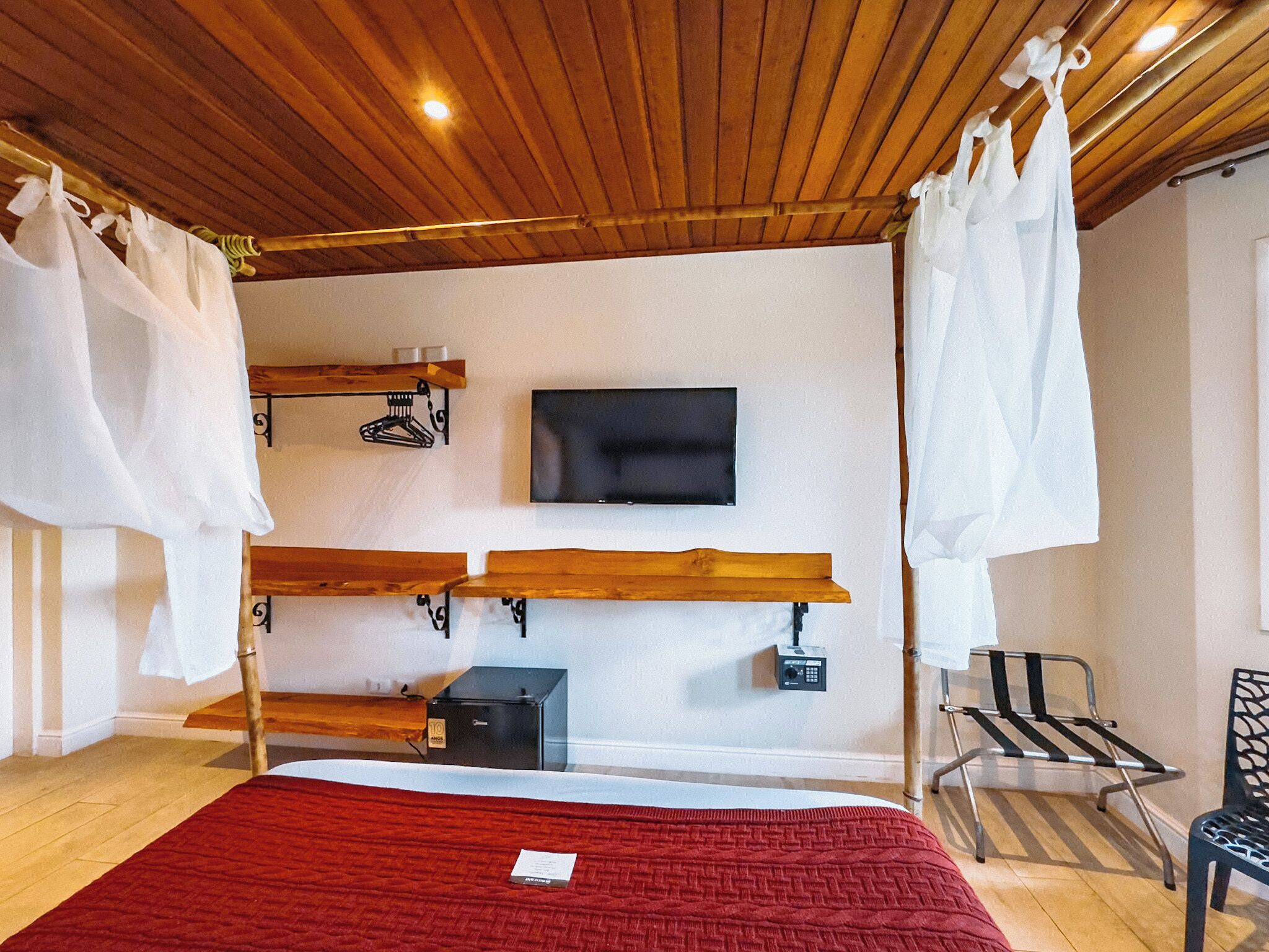 A bedroom with a bed, a TV, a wardrobe, and a bench.