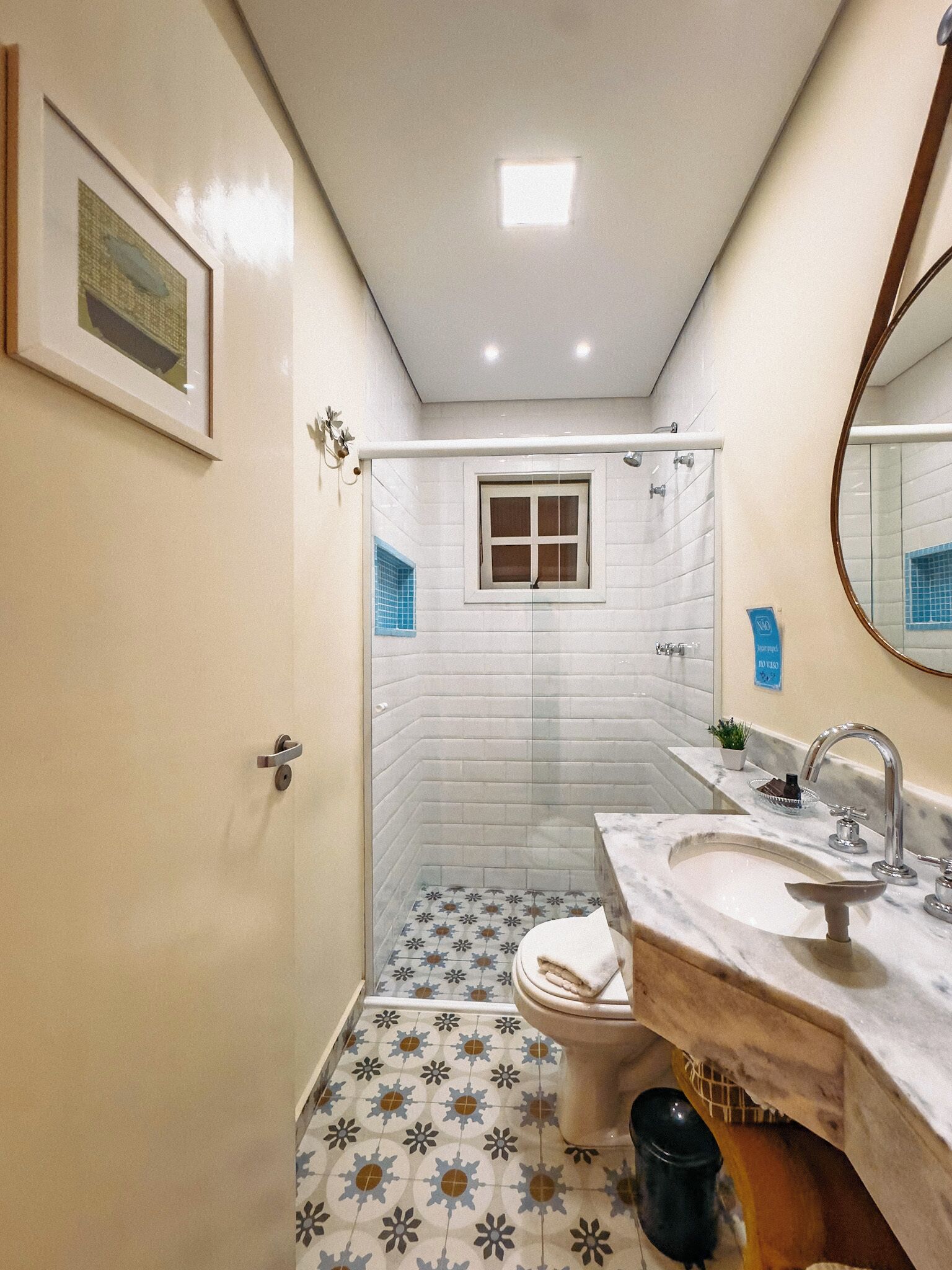 Un baño con ducha, inodoro, lavamanos y un cuadro en la pared.