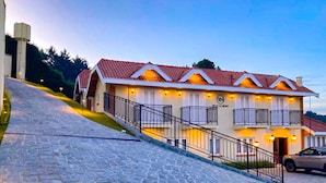A hotel with a stone staircase leading to a building with a red-tiled roof and balconies.
