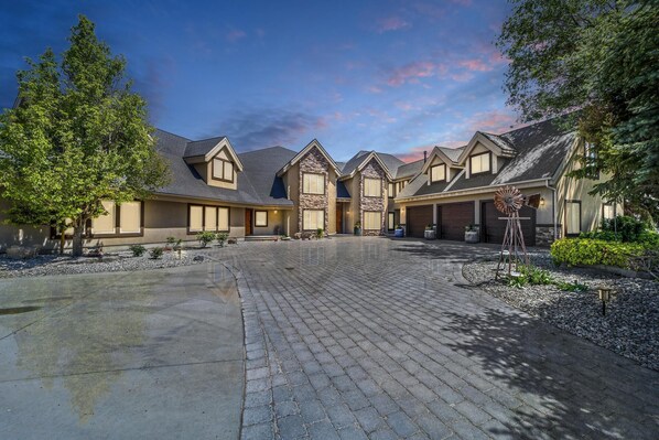 A residential building with a paved driveway, multiple entry points, and a landscaped garden area. - Canyon Rim Retreat (Filer)