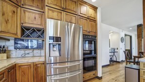 A kitchen with wooden cabinets, a stainless steel refrigerator, a built-in oven, and a coffee maker. - Canyon Rim Retreat (Filer)
