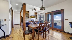 A dining area with a wooden table and chairs, a ceiling fan, and a view through glass doors. - Canyon Rim Retreat (Filer)
