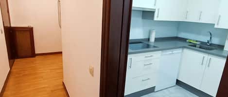 A kitchen with white cabinets, a sink, and a countertop.