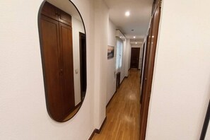 Een hal met houten vloer, een houten deur en een spiegel aan de muur.