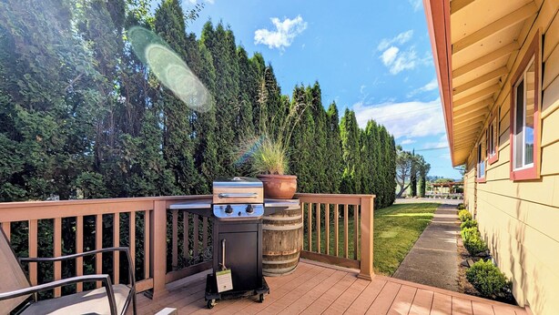 A wooden deck with a barbecue grill and a cart, surrounded by a wooden railing and a pathway leading to a house. - Country View Cottage #2: Unwined (Carlton)