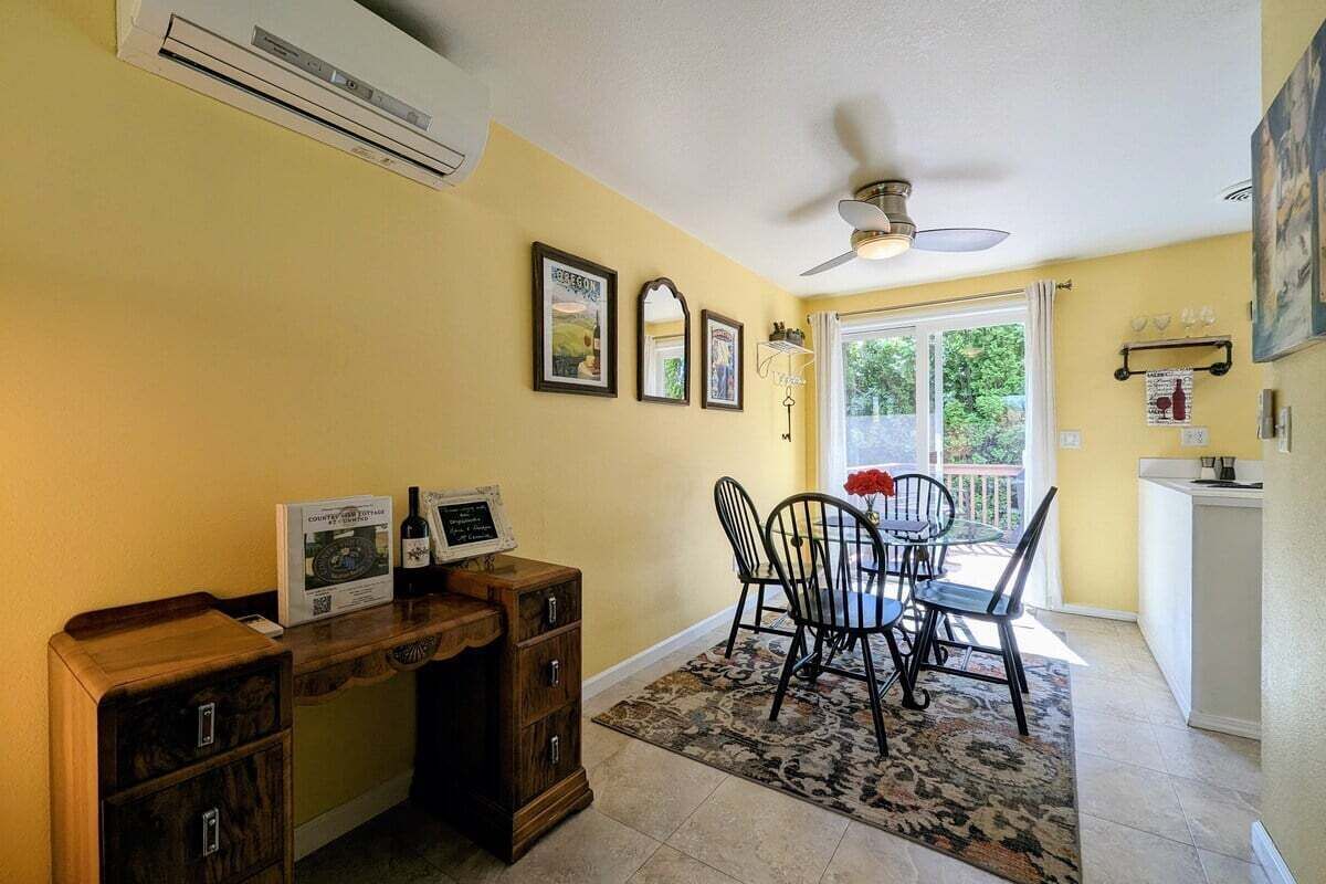A dining area with a table and chairs, an air conditioning unit, and a ceiling fan.
