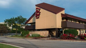 Un hôtel Red Roof Inn avec une façade beige, un toit brun et un parement en pierre.