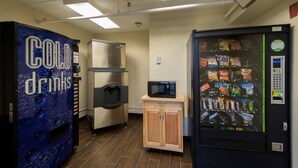 Un espace de vente proposant une machine à boissons fraîches, un four à micro-ondes et une machine à distributeur de collations.