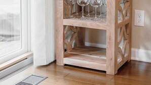 A wooden wine rack with three shelves, a framed picture, and a candle holder.