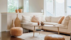 A modern living room with a white sofa, a small coffee table, and a large window with blinds.