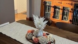 A dining area with a wooden table, a white rug, and a decorative centerpiece. - Elegant charm! (West Allis)