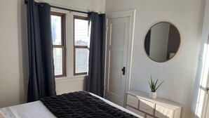A bedroom with a bed, a dresser, a mirror, and a window with curtains. - Elegant charm! (West Allis)