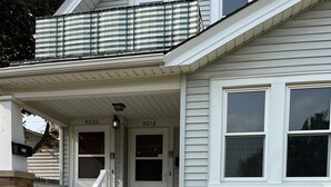 A two-story house with a front porch, a mailbox, and a flower pot. - Elegant charm! (West Allis)
