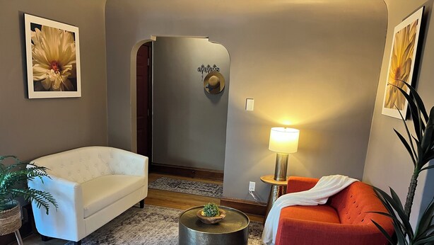 A living room with a white sofa, an orange sofa, a round coffee table, a lamp, and a painting on the wall. - Elegant charm! (West Allis)