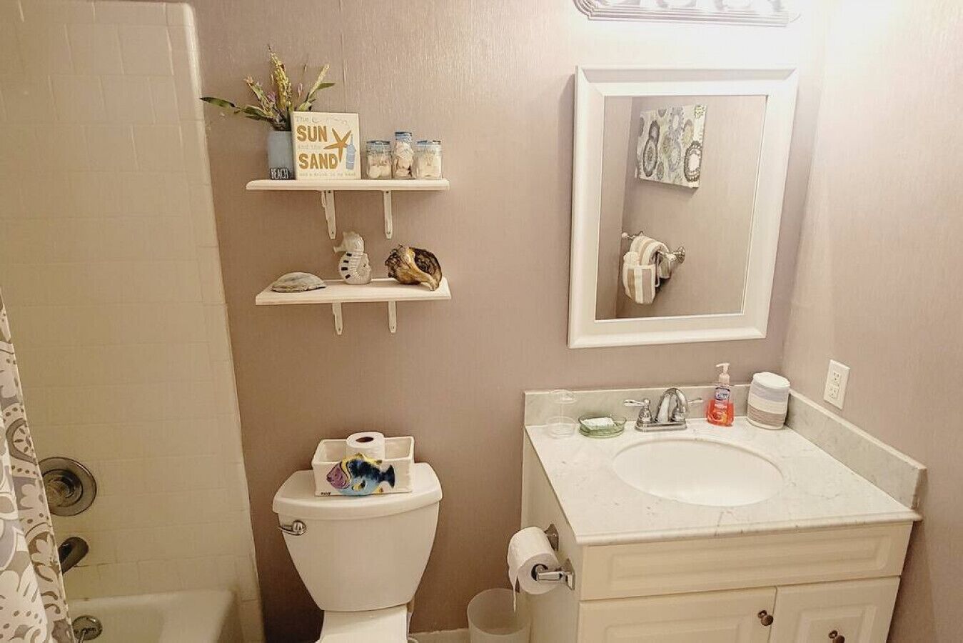 Een badkamer met toilet, wastafel en een plank met toiletartikelen.